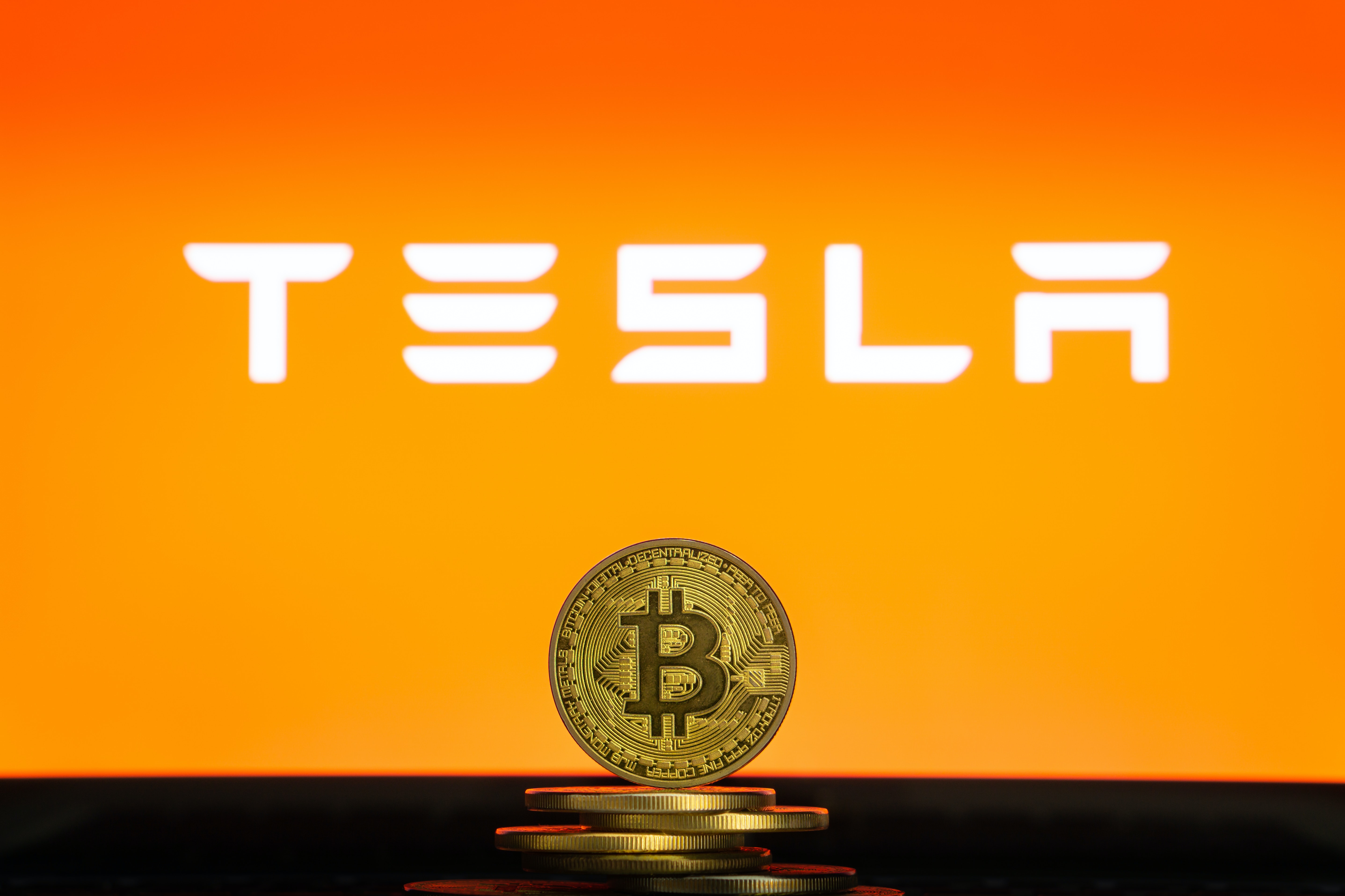 Tesls logo in front of a bitcoin