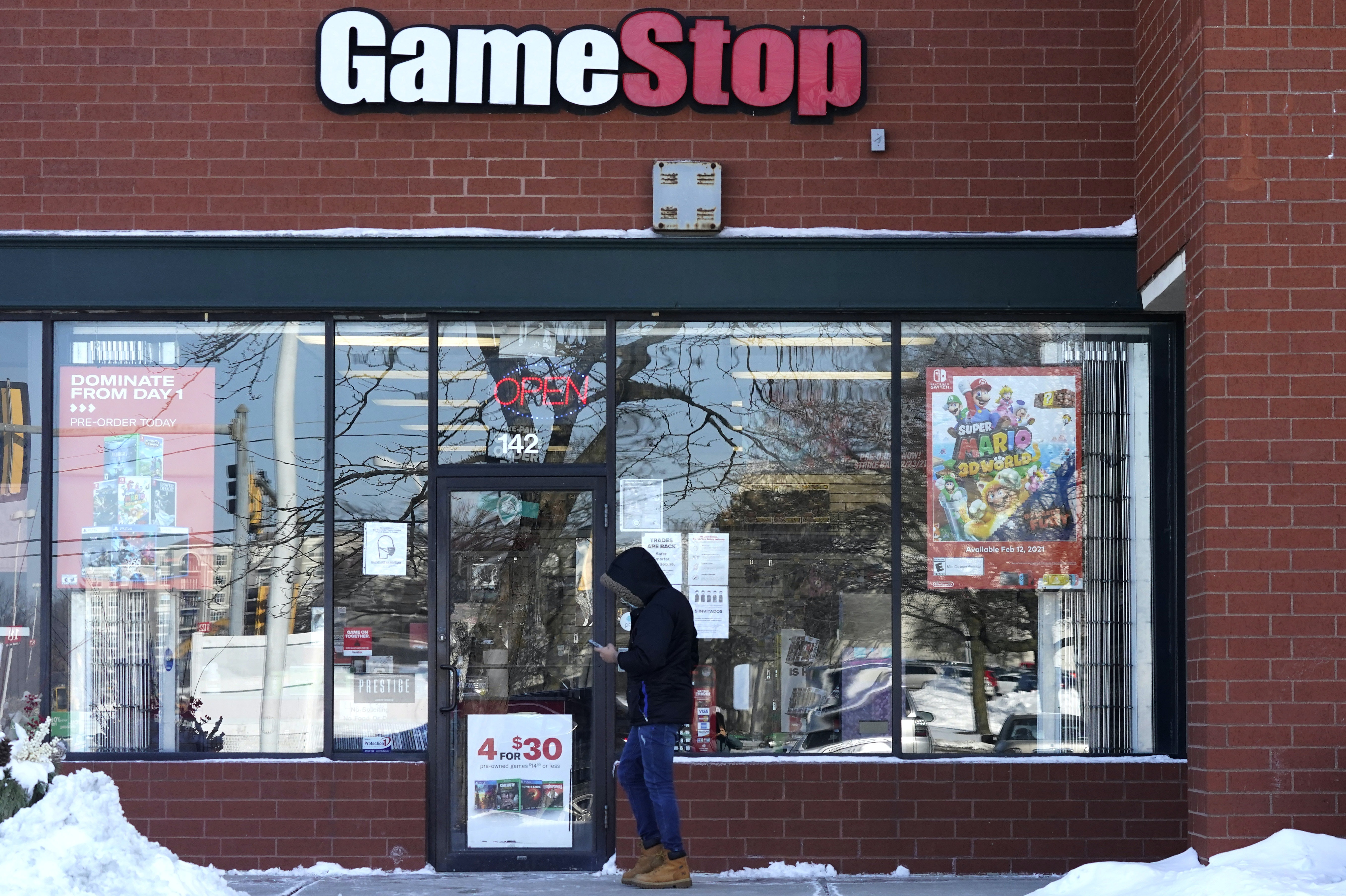 A customer checks on his cellphone as he walks to a GameStop store.