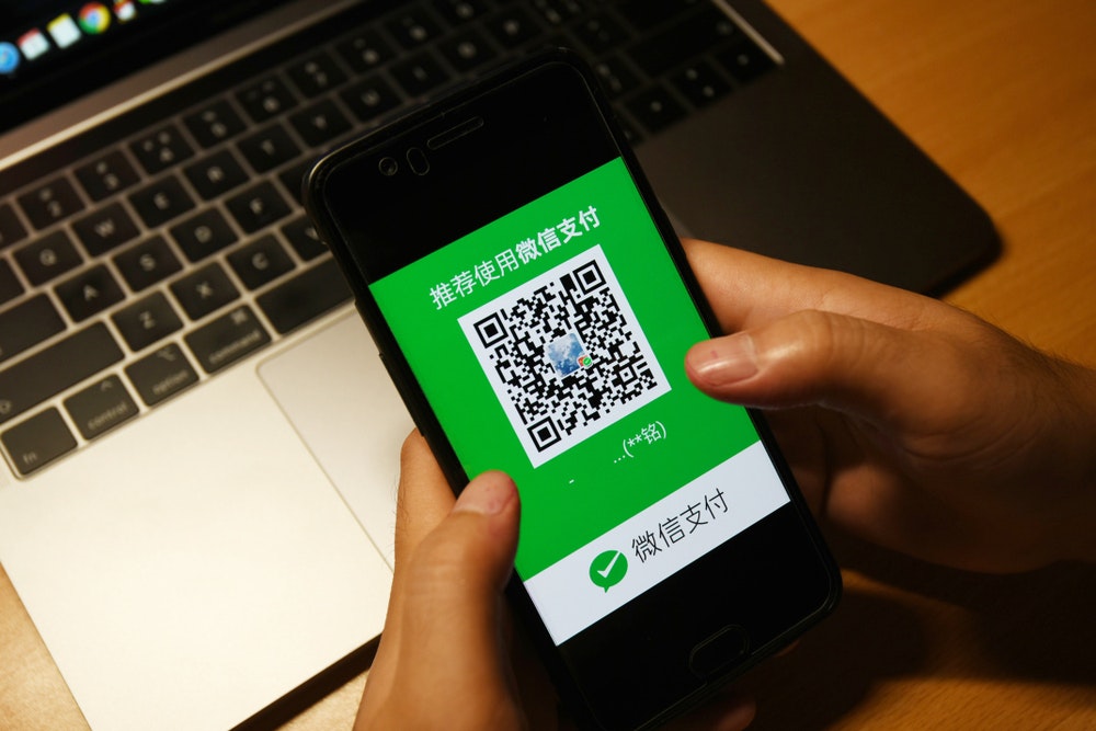 Someone holding a smartphone using the WeChat app to make a payment